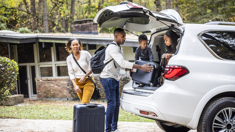 family loading suitcases into the back of a car