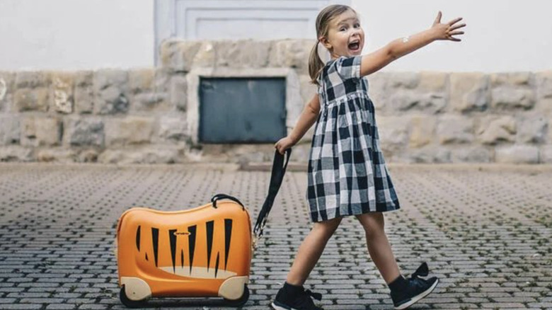 little girl pulls her lion printed Samsonite Dream Rider suitcase
