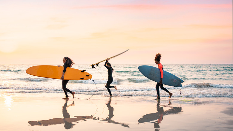 Surfers carrying boards into the water