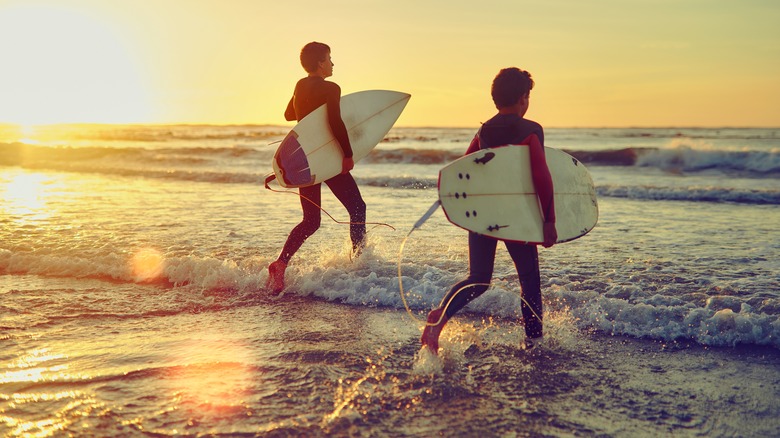 Two surfers running into the ocean