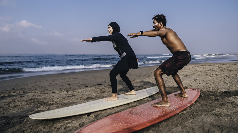 Two people practicing surfing on the beach