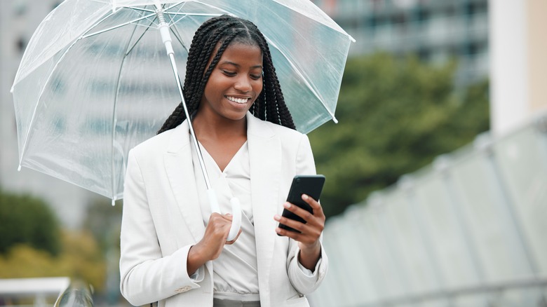 Woman with umbrella checking phone