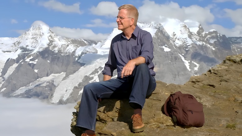 Rick Steves sitting alps in background