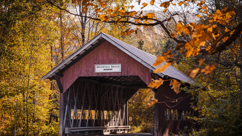 Covered red Brookdale Bridge in Vermont surrounded by colorful autumnal foliage