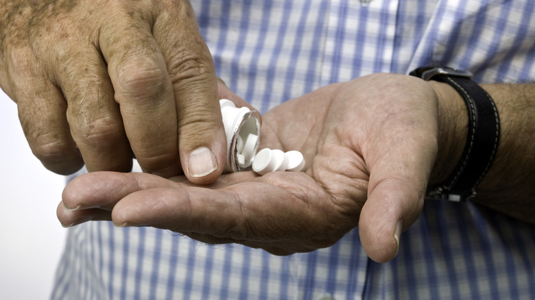 Man pouring pills in hand