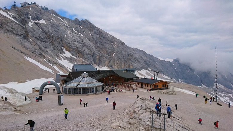 Mountaintop area with outdoor restaurant seating and people walking around
