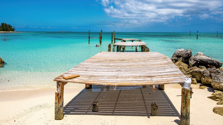 An old pier extends into turquoise water at Jaws Beach, Bahamas
