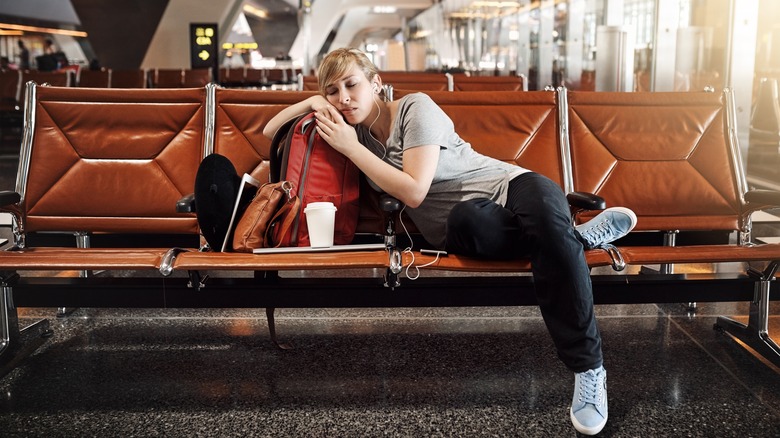 woman waits at the airport asleep on her luggage