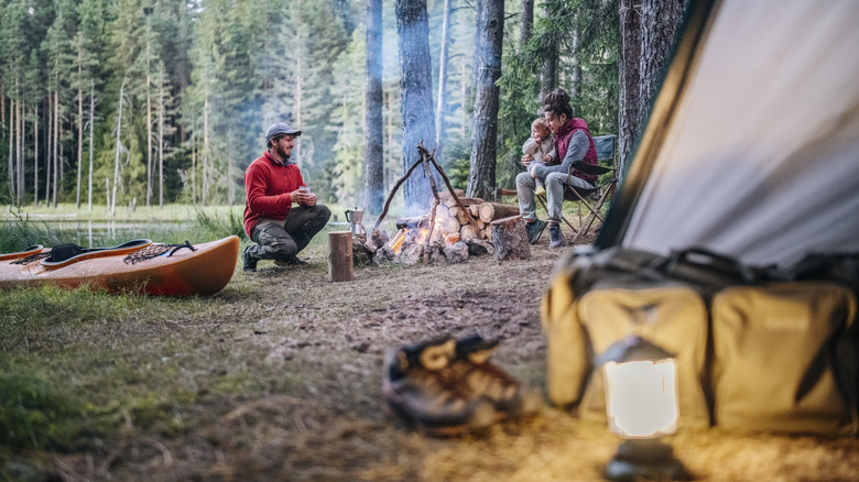 A family camping near a firepit and canoe
