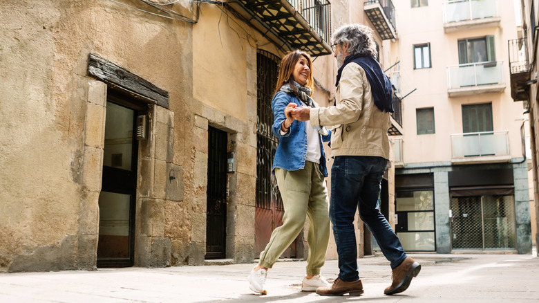 Happy senior couple dancing on a European alley near ancient stone buildings