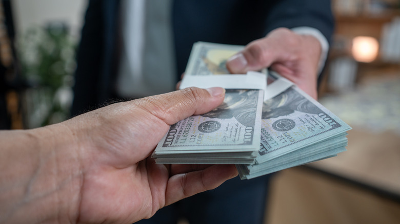 A man handing over hundreds of dollars to another person