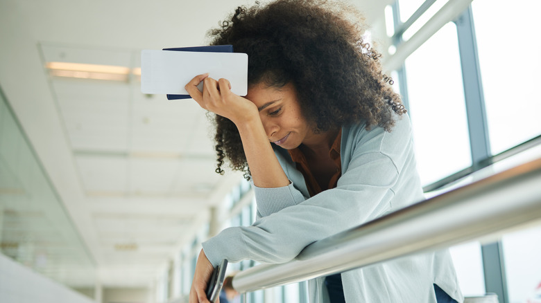 A stressed woman leans on a ledge in an airport