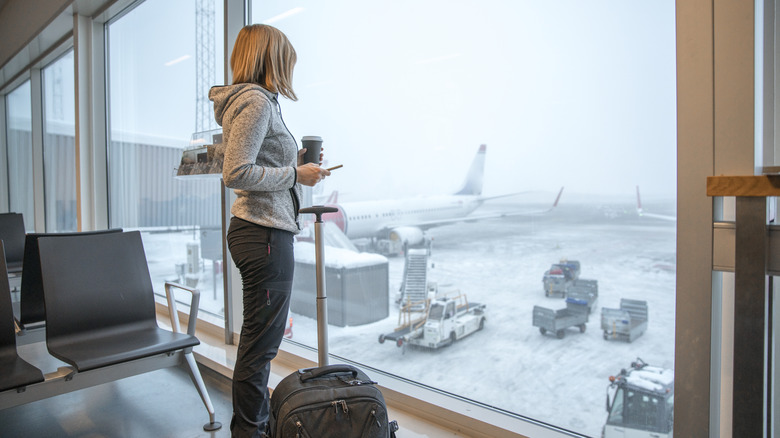 Traveler looking out airport gate window