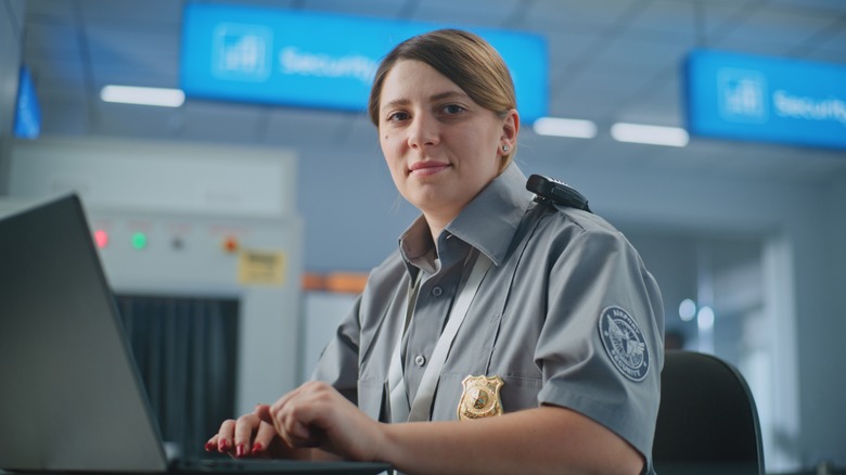 A TSA agent taps at a computer near an airport checkpoint