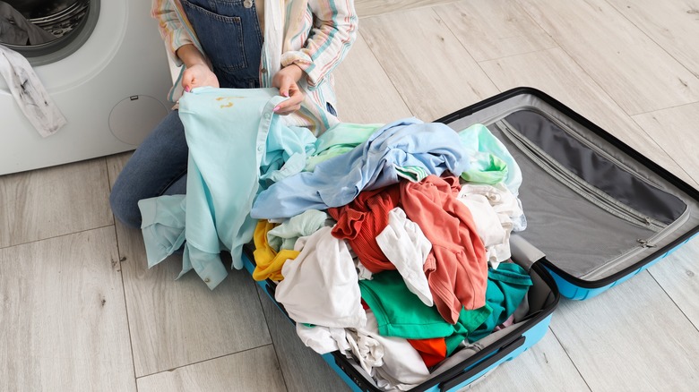A woman cleaning dirty clothes from her suitcase