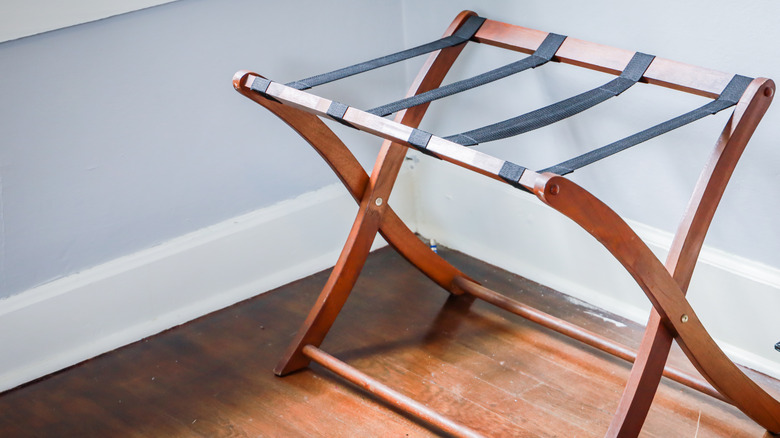 A wooden luggage rack in the corner of a room