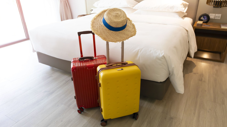 Two suitcases and a hat in front of a vacation rental bed