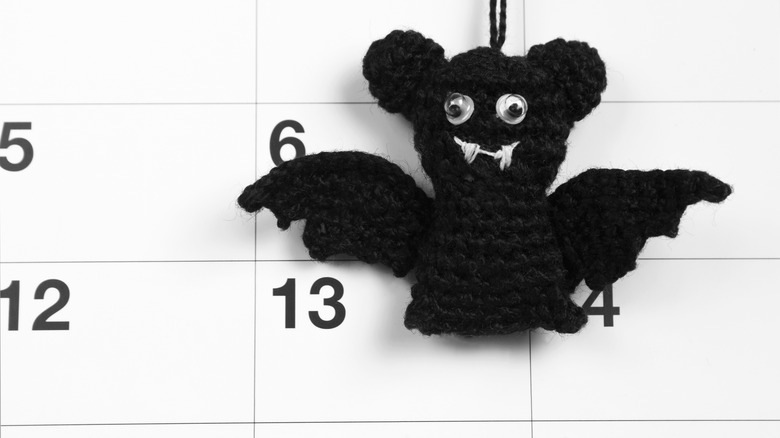 A woven bat figure dangles over a calendar's 13th day of the month.