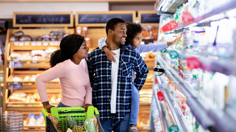 a young family smiling in a supermarket aisle