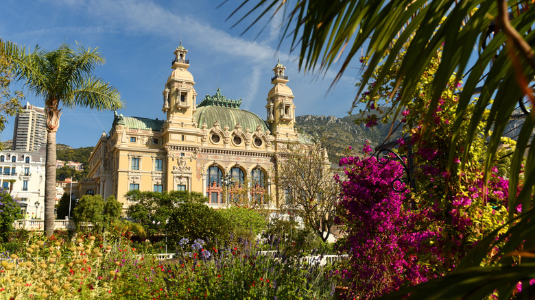 An opulant building exterior surrounded by palm trees and colorful flowers