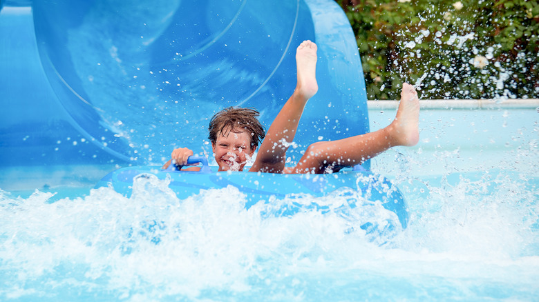 Young boy sliding into pool