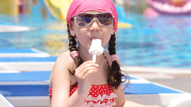 Child eating ice cream poolside