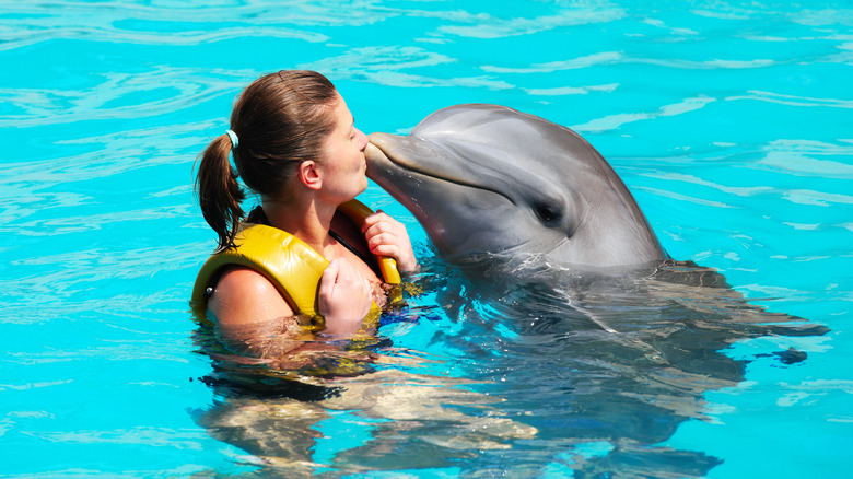 A woman kissing a dolphin 