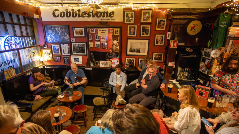 Two folk musicians play violin and bagpipes for visitors in Cobblestone pub