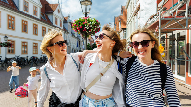 Three happy women walking arm in arm through a German town