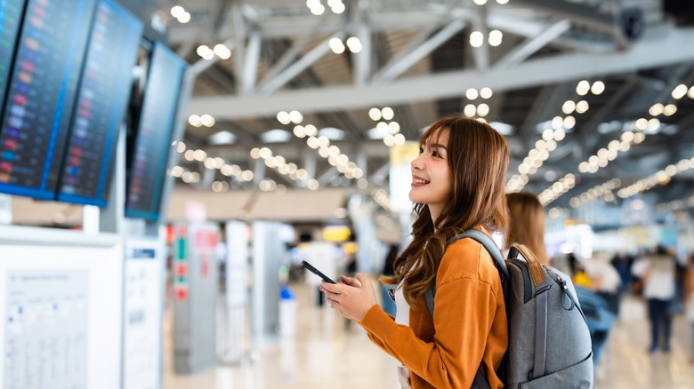 person in airport checking board
