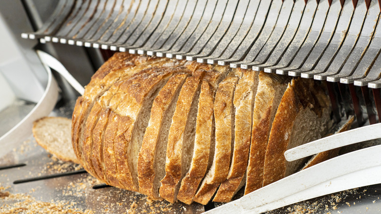 Loaf of bread being run through a bread slicing machine