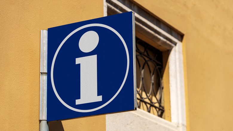 Blue tourist information symbol on yellow wall