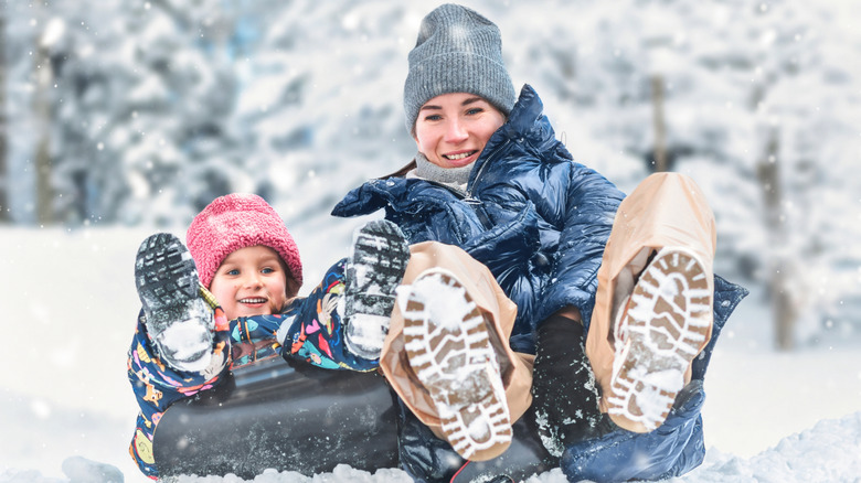 mom and child sledding in snow