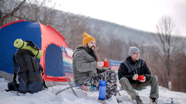 two people sitting outside tent in snow
