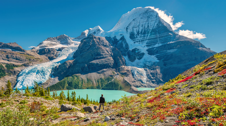 Person looking at a turquoise lake below Mt Robson
