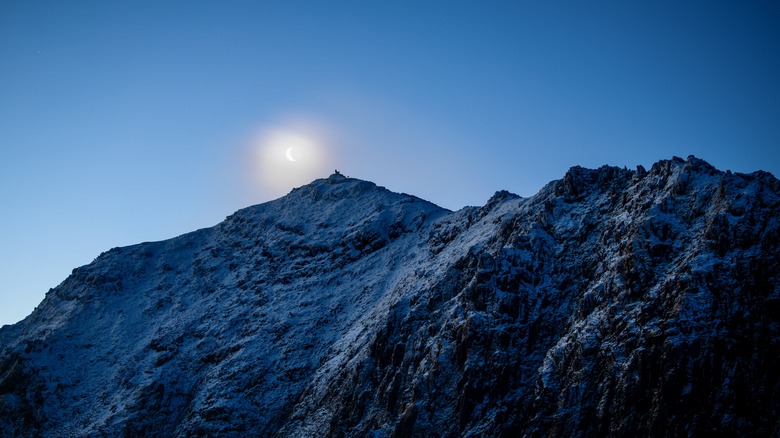 The moon rising behind the summit of Snowdon mountain in Wales