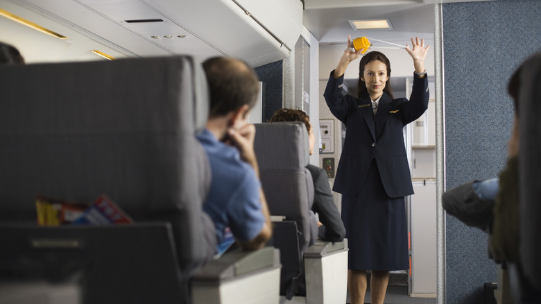 A flight attendant demonstrating safety procedures on a plane.