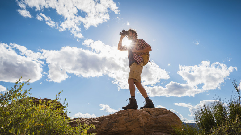 A hiker looks through a pair of binoculars in the desert