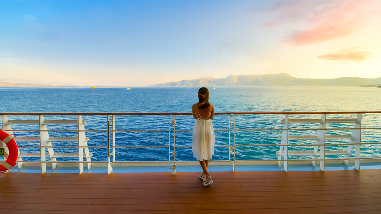 A woman on a cruise deck looking over the ocean.