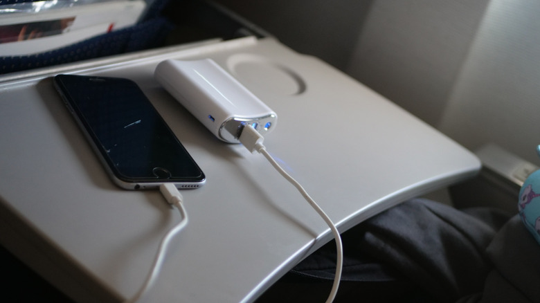 A portable charger and phone on a tray table.