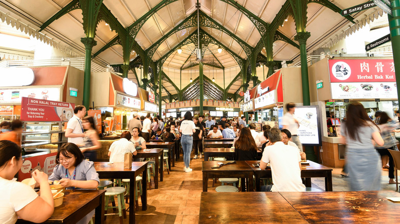 Hawker stalls at the Lau Pa Sat dining hall with tables and chairs.