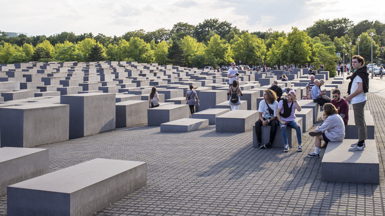 tourists sitting on concrete slabs at Berlin Holocaust Memorial
