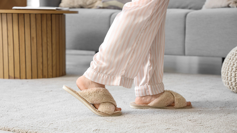 A woman wearing soft sandal slippers inside on a rugged living room floor