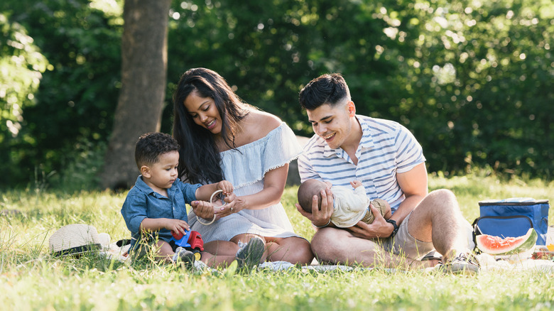 A family picnics on grass near trees in Pelham Bay Park