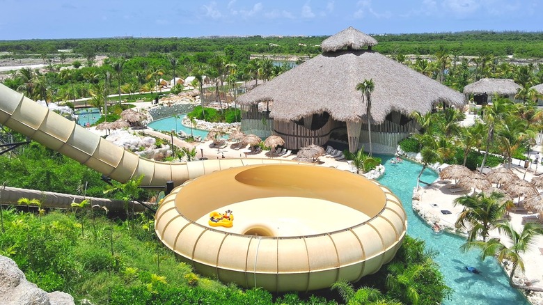 giant slide, lazy river, pools, greenery and thatched-roof building at El Dorado Water Park