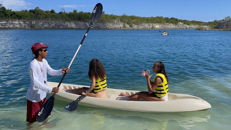 two kayakers on a double kayak in a big lake and an El Dorado Water Park staff member assisting with the launch