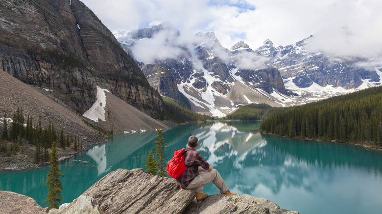 a hiker sitting down looking at Canada's mountains and lakes