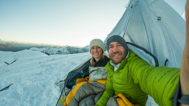 Two people in a tent with snow outside