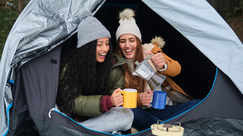 Two women drinking tea in a tent.