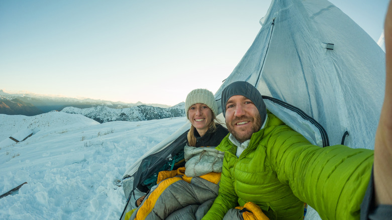 A couple camping in the snow.